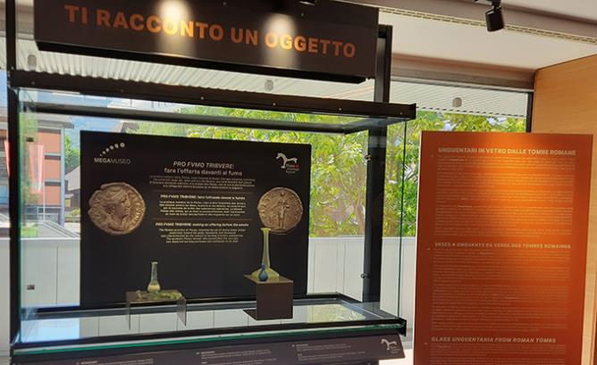 Vetrina allestita al MegaMuseo con, a sinistra, gli unguentari provenienti dal sito su cui sorge l'area espositiva e, a destra, quelli provenienti dalle collezioni del MAR. Qui in alto la descrizione degli oggetti esposti.