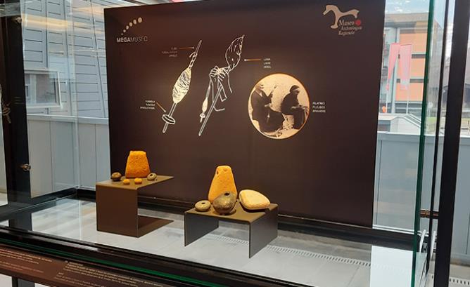 Vetrina allestita al MegaMuseo con, a sinistra, i pesi da telaio provenienti dal sito su cui sorge l'area espositiva e, a destra, quelli provenienti dalle collezioni del MAR. Qui in alto la descrizione degli oggetti esposti.